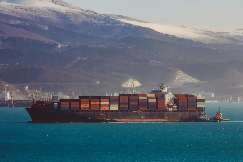 a large cargo ship in the ocean with mountains in the background